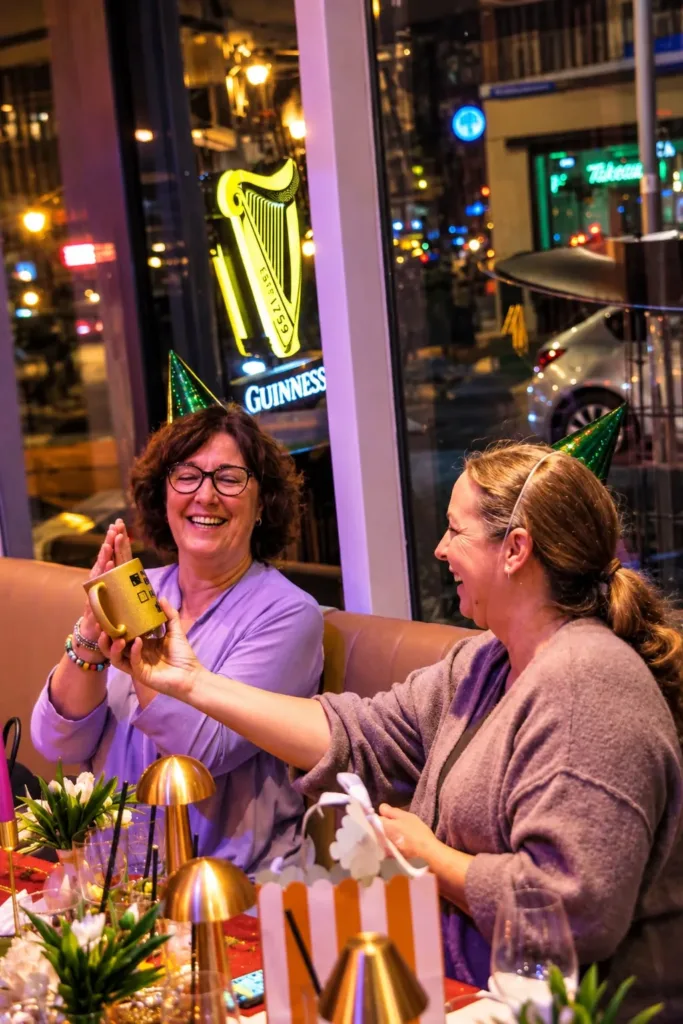 Twee lachende vrouwen proosten samen aan tafel bij de Guinness-neon in Broox Rotterdam tijdens de kerstdagen